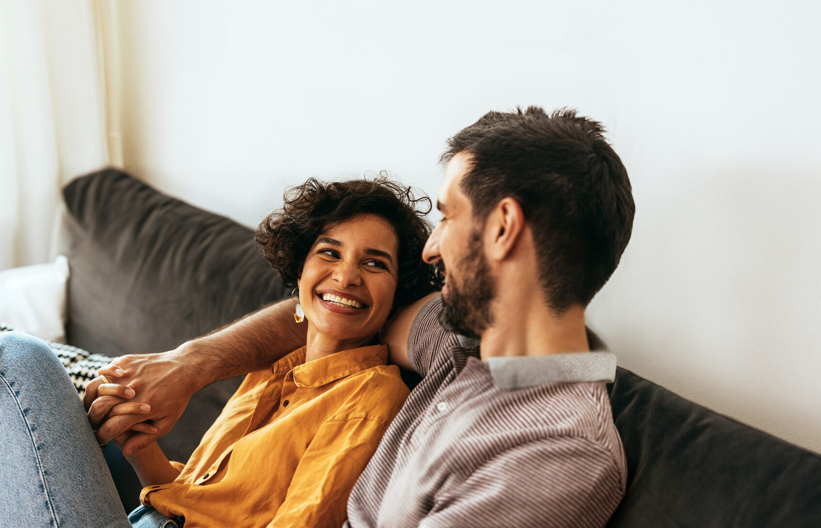 happy man and woman on sofa holding hands